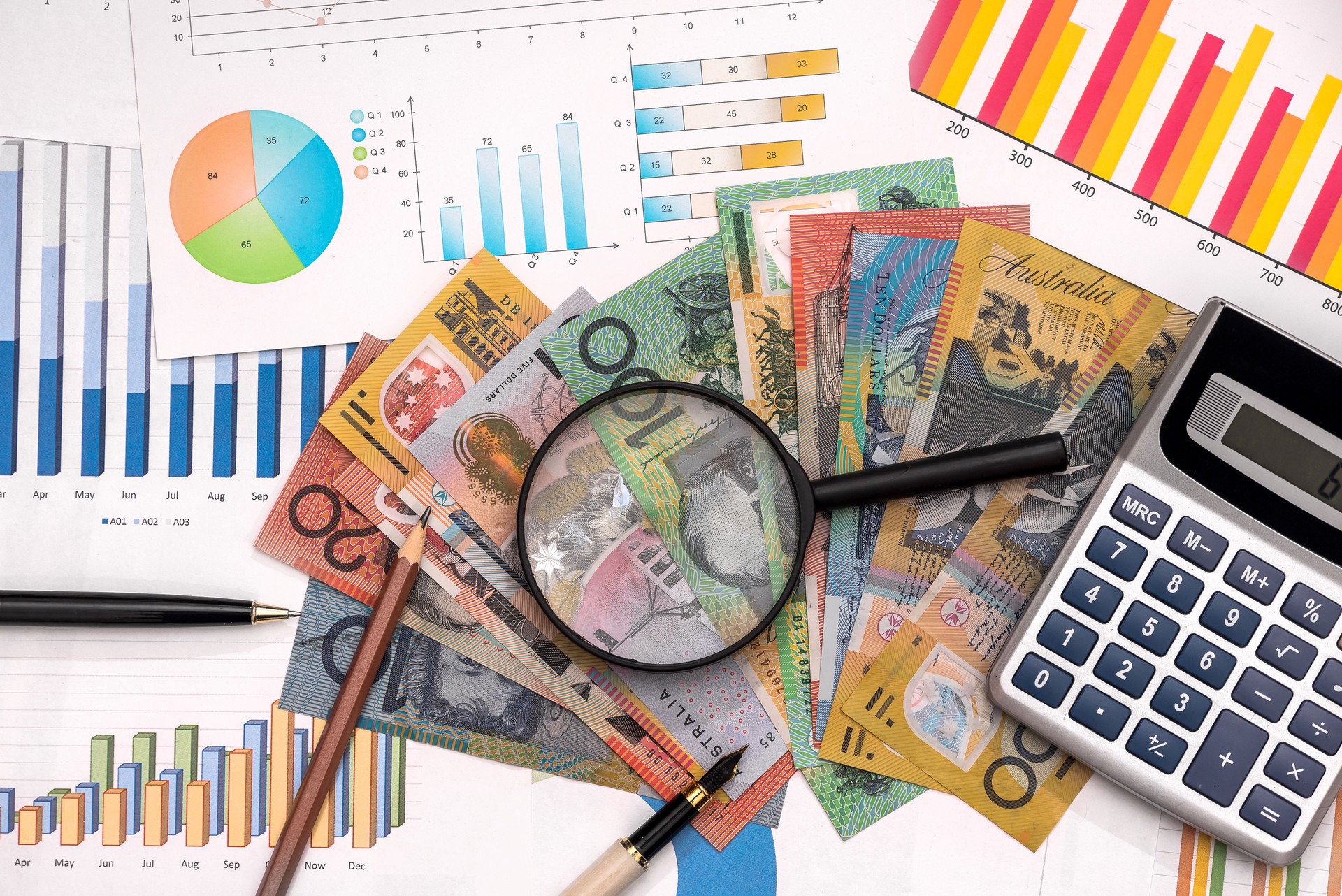 Business graphs with australian dollars, magnifier, pen and calculator
